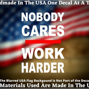 May include: A white decal with the text "Nobody Cares Work Harder" on a blurred American flag background. The text is in all caps and the words "cares" and "work" are underlined in red.