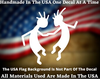 May include: White vinyl decal of two stick figures dancing, with the text "Handmade in the USA One Decal at a Time" and "All Materials Used Are Made in the USA". The decal is shown against a blurred American flag background.