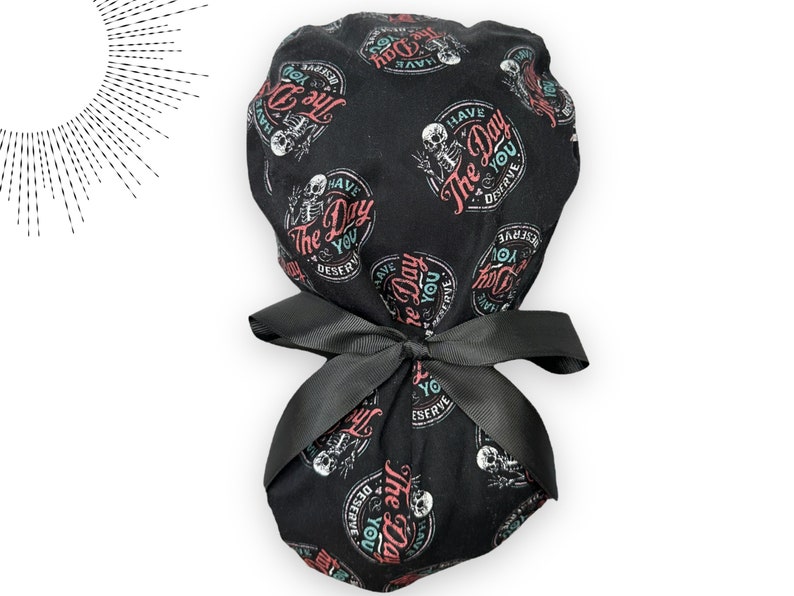 Puede incluir: Gorro quir&uacute;rgico negro con un patr&oacute;n repetido de esqueletos y la frase "Have The Day You Deserve", con un lazo negro. Dise&ntilde;ado para uso m&eacute;dico.