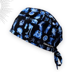 May include: A black surgical scrub cap featuring a repeating pattern of blue-toned X-ray images of bones and organs. The cap has a tie closure at the back and the text "SUNSHINE CUPS CO." is visible on the side.