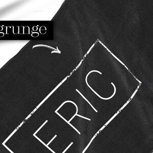 K&ouml;nnte beinhalten: Schwarzes Handtuch mit einem wei&szlig;en Rechteck und dem Wort "ERIC" darin. Das Rechteck hat einen Grunge-Effekt.