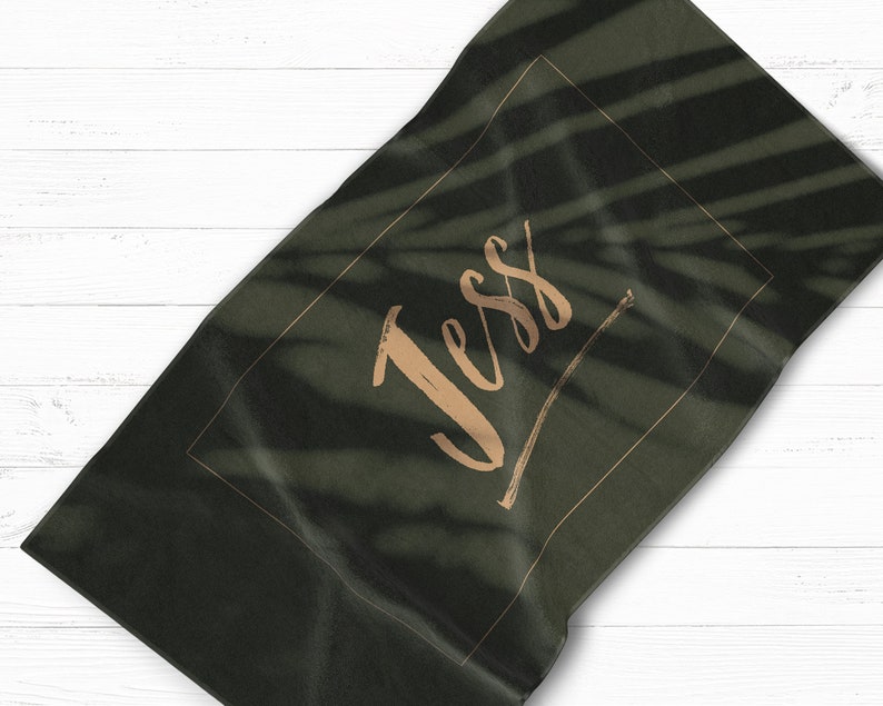 May include: A dark green beach towel with a gold frame and the name "Jess" written in gold script.