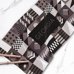May include: A black and white geometric patterned towel with the word "GEORGIA" in white text on a black background.