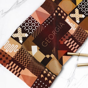 May include: A brown and beige geometric patterned fabric with the word "GEORGIA" in white text.