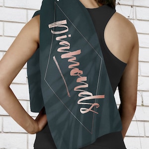 May include: A dark green yoga towel with a diamond-shaped design and the word "Diamonds" written in rose gold lettering.