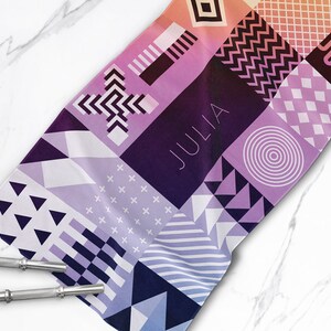 May include: A colorful geometric patterned towel with the name "JULIA" printed in white on a purple background.