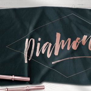 May include: A dark blue yoga towel with the word "diamond" written in rose gold lettering inside a diamond shape.
