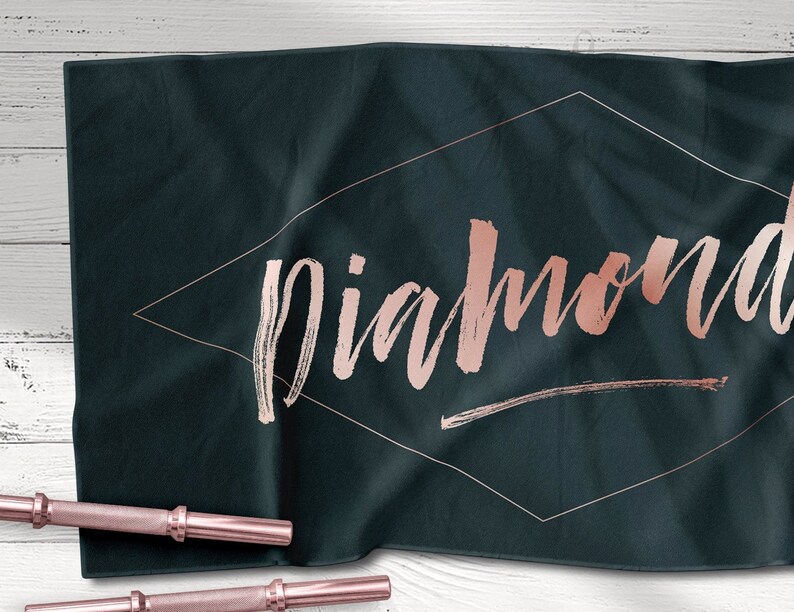 May include: A dark blue yoga towel with the word "diamond" written in rose gold lettering inside a diamond shape.