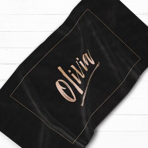 May include: Black beach towel with a gold frame and the name "Olivia" written in gold script.