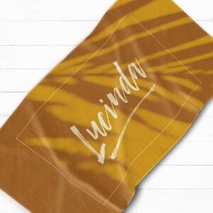 May include: A yellow beach towel with a white palm leaf pattern and the name "Lucinda" written in white cursive script.