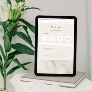 May include: A digital tablet displays a website with the text "What To Expect" and a four-step process. The tablet rests on a stack of books, with a vase of white flowers and green leaves in the background.