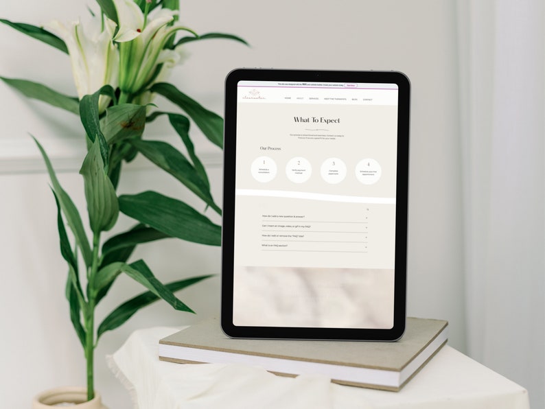 May include: A digital tablet displays a website with the text "What To Expect" and a four-step process. The tablet rests on a stack of books, with a vase of white flowers and green leaves in the background.