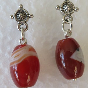 Puede incluir: Un par de pendientes colgantes con cuentas de piedra de cornalina roja y detalles de filigrana plateada.
