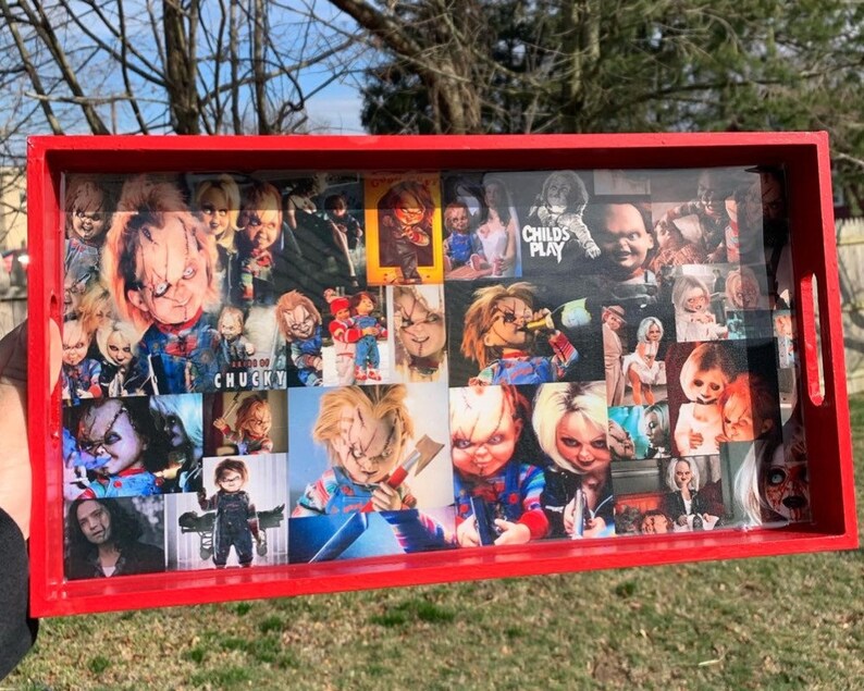 Puede incluir: Una bandeja rectangular roja con un collage de im&aacute;genes de la mu&ntilde;eca Chucky de la serie de pel&iacute;culas de terror Child's Play. Las im&aacute;genes est&aacute;n dispuestas en un patr&oacute;n de cuadr&iacute;cula y est&aacute;n cubiertas con un acabado transparente y brillante.