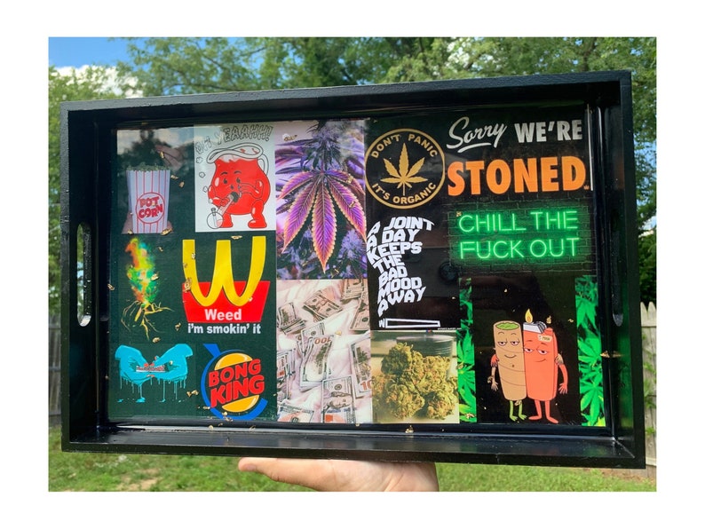 Puede incluir: Una bandeja rodante rectangular negra con un collage de im&aacute;genes y texto. El collage incluye im&aacute;genes de cannabis, dinero y personajes de dibujos animados. El texto incluye "Sorry We're Stoned" y "Chill the F*ck Out".