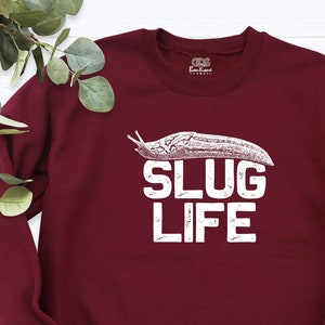 May include: Burgundy sweatshirt with a white graphic of a slug and the text "SLUG LIFE".