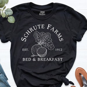 May include: Black t-shirt with white text that reads "Schrute Farms Est. 1912 Bed & Breakfast" with a drawing of a beet.