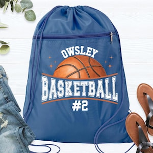 May include: A blue drawstring backpack with a basketball graphic. The bag features the name "Owsley" above a basketball image, with "BASKETBALL" and the number "#2" below. The bag has a zippered pocket and blue drawstrings.