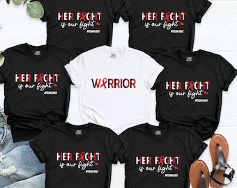 May include: Six black t-shirts with white text and a red ribbon design. The text on the shirts reads "Her Fight is our Fight" and "Warrior".
