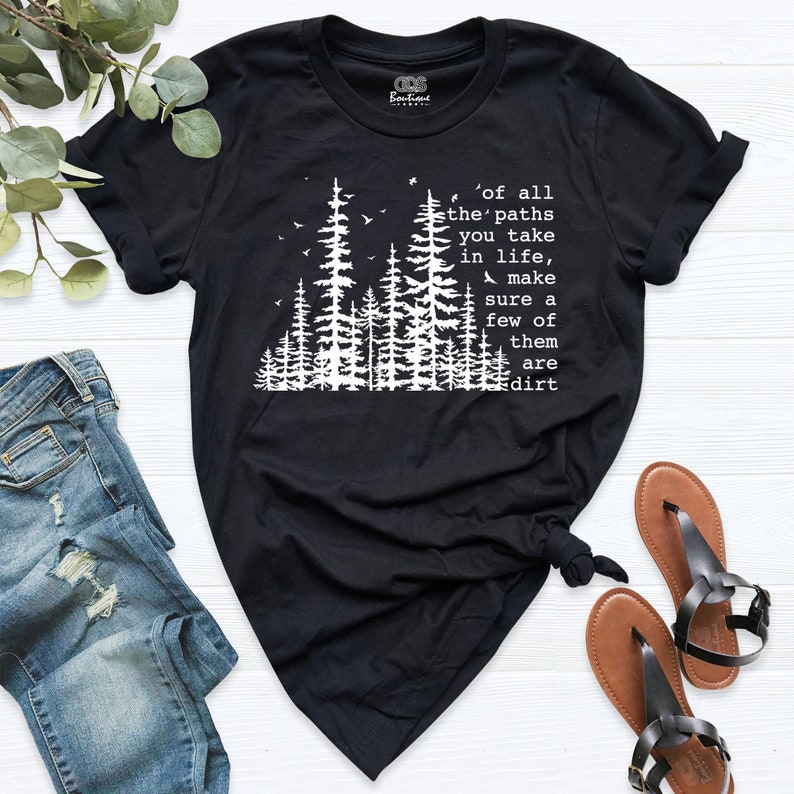 Op de afbeelding: Zwart T-shirt met een witte afbeelding van een bos en de tekst 'of all the paths you take in life, make sure a few of them are dirt'.