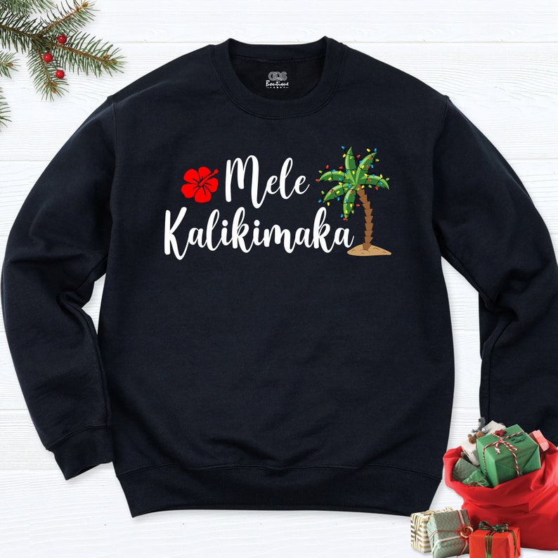 May include: Black sweatshirt with a white graphic of a palm tree with Christmas lights, a red hibiscus flower, and the text "Mele Kalikimaka".