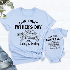 May include: Light blue t-shirt and onesie set with the text "OUR FIRST FATHER'S DAY" and a turtle graphic. The text "2026 Bailey & Daddy" is below the turtle. A matching onesie is also included.