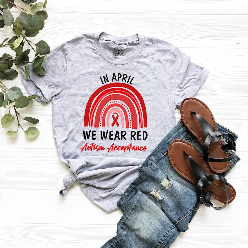 May include: A gray t-shirt with a red rainbow and the text "In April We Wear Red Autism Acceptance".