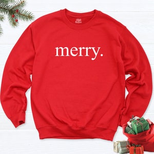May include: Red Christmas sweatshirt with the word "merry" printed in white on the front.
