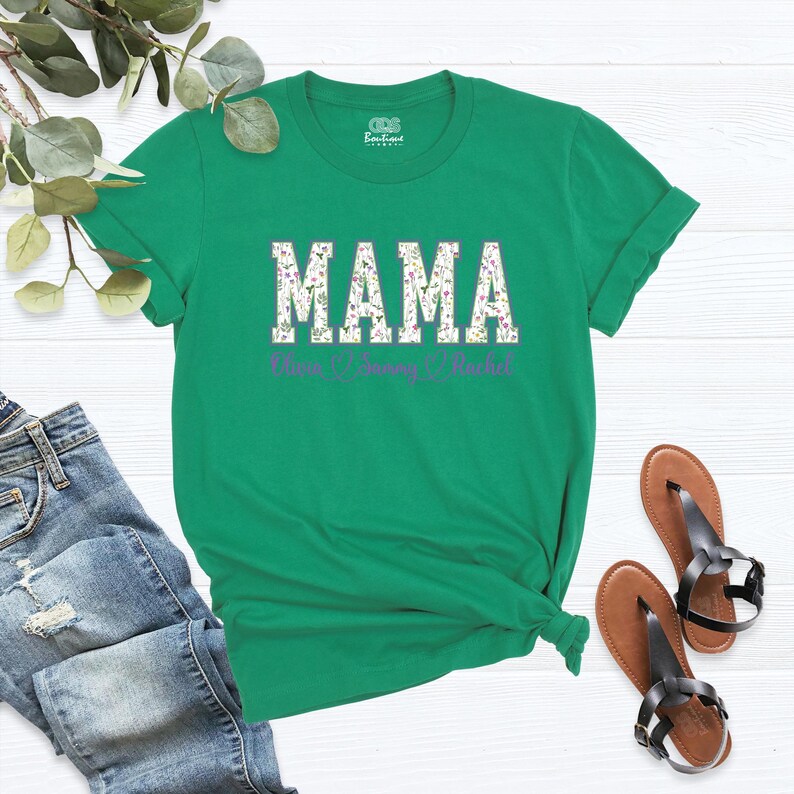 Puede incluir: Camiseta verde con la palabra "MAMA" en letras blancas con un patr&oacute;n floral. Los nombres "Noah", "Sunny" y "Rachel" est&aacute;n escritos en morado debajo de la palabra "MAMA".