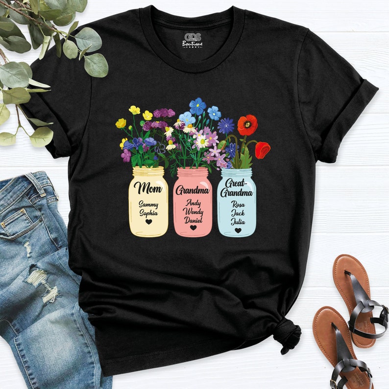 May include: Black t-shirt with a design of three mason jars filled with colorful flowers. Each jar has a label that says "Mom", "Grandma", and "Great-Grandma" with names listed underneath.