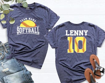 May include: A heather navy blue t-shirt featuring a yellow softball graphic with the text TEAM NAME SOFTBALL on the front and the name LENNY with the number 10 in yellow softball-textured font on the back of the garment.
