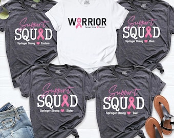 May include: Five t-shirts featuring breast cancer awareness designs. Four dark gray shirts display the text Support SQUAD with a pink ribbon and the words Springer Strong. One white shirt displays the text WARRIOR with a pink ribbon.