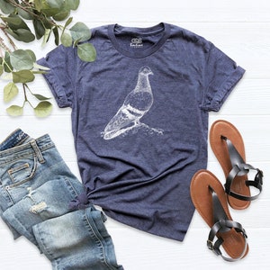 Op de afbeelding: Een marineblauw t-shirt met een witte afbeelding van een duif. Het t-shirt is gemaakt van een zacht, comfortabel materiaal.