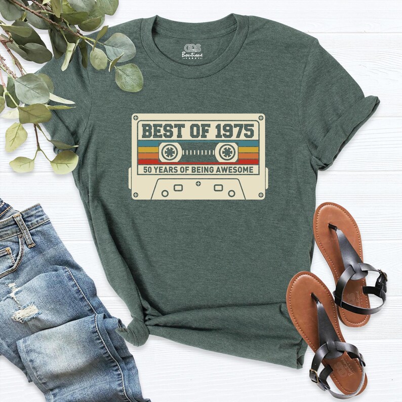 K&ouml;nnte beinhalten: Ein gr&uuml;nes T-Shirt mit einer Vintage-Kassettengrafik, auf der "Best of 1975" und "50 Years of Being Awesome" steht.