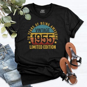 Op de afbeelding: Zwart T-shirt met een vintage-stijl grafische afbeelding met de tekst "70 Years of Being Awesome Vintage 1955 Limited Edition".