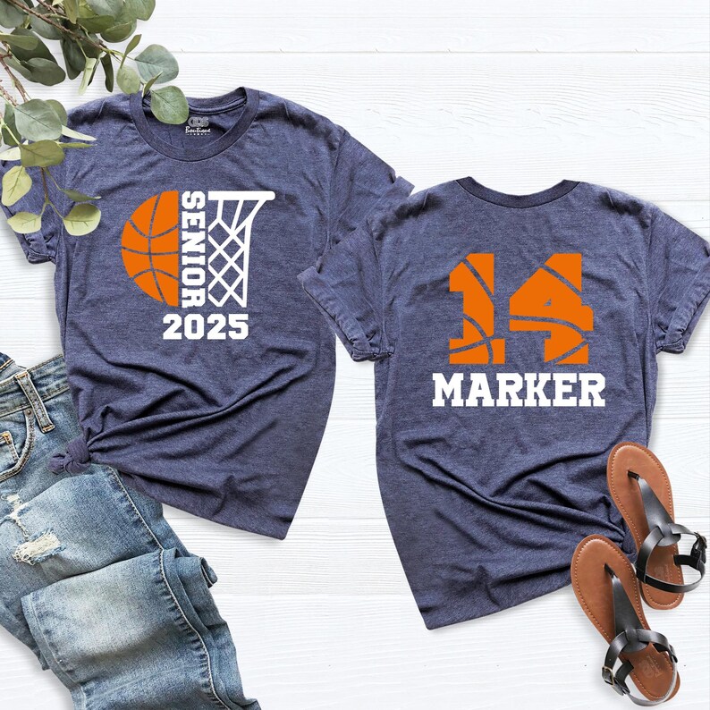 May include: Two navy blue t-shirts with basketball-themed designs. The front shirt has a basketball and hoop with the text "Senior 2025". The back shirt has a basketball with the number "14" and the text "Marker".