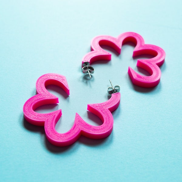 Une paire de boucles d'oreilles créoles en forme de fleur rose vif imprimées en 3D