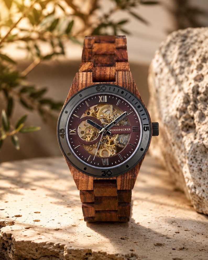 May include: A wooden wristwatch with a dark burgundy face and a visible mechanical movement. The watch has a dark gray bezel and a wooden band. The watch face displays Roman numerals and the brand name "WOODPECKER".