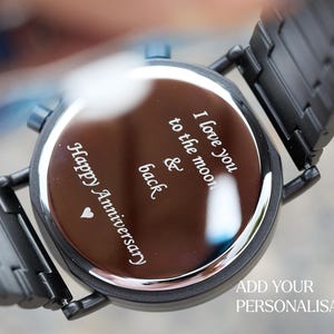 Puede incluir: Reloj de pulsera negro con una esfera plateada y un mensaje grabado: "Happy Anniversary, I love you to the moon & back".