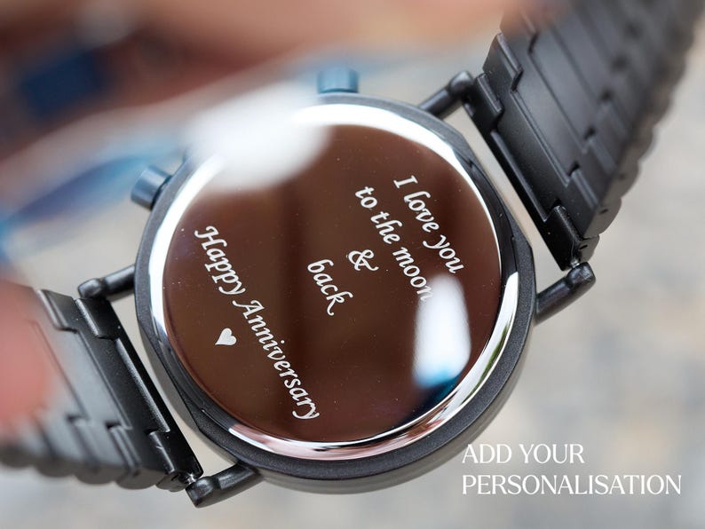Puede incluir: Reloj de pulsera negro con una esfera plateada y un mensaje grabado: "Happy Anniversary, I love you to the moon & back".