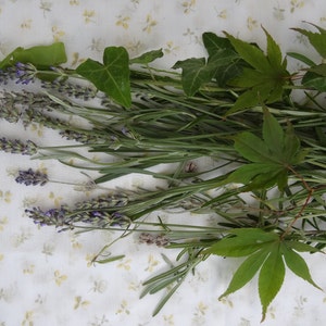 K&ouml;nnte beinhalten: Ein Strau&szlig; frischer Kr&auml;uter und Lavendelbl&uuml;ten, darunter Rosmarin, Efeu und Ahornbl&auml;tter.