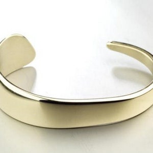 Op de afbeelding: Een eenvoudige gouden armband met een gladde, gepolijste afwerking.