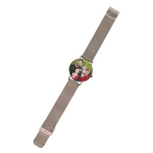 May include: A wristwatch with a metallic silver mesh strap and a round face. The watch dial features a colour photograph of a family of three, including an adult and two children, with thin silver hands indicating the time over the image.