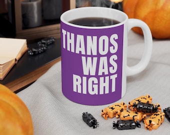 Könnte beinhalten: Lilafarbener Kaffebecher mit weißem Text, der "THANOS WAS RIGHT" lautet. Der Becher steht auf einer hellbraunen Oberfläche mit orangefarbenen und schwarzen Süßigkeiten.
