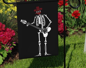 May include: A black garden flag featuring a white skeleton wearing a red bandana and cowboy hat playing a white electric guitar.