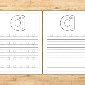 May include: Two white worksheets with the lowercase letter "a" printed on them. The worksheets have a large "a" with numbered arrows for tracing, and lines for practicing writing the letter. The background is a light brown wood.