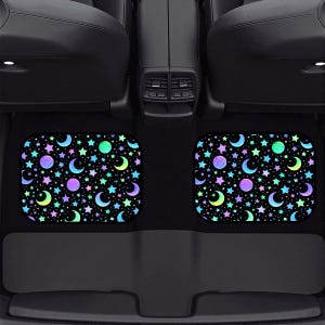 May include: Two car floor mats with a black background and a colorful celestial pattern of stars, moons, and planets. The mats are rectangular with rounded corners and are placed in a car.