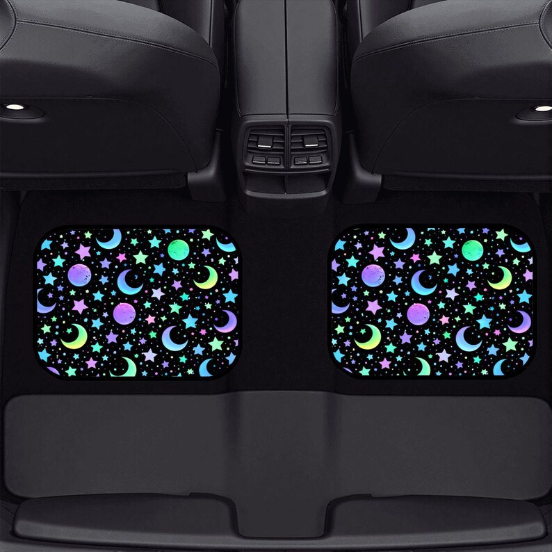 May include: Two car floor mats with a black background and a colorful celestial pattern of stars, moons, and planets. The mats are rectangular with rounded corners and are placed in a car.