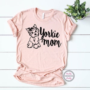 May include: A pink t-shirt with a black silhouette of a Yorkshire Terrier and the text "Yorkie Mom".