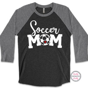 May include: A black and gray baseball tee shirt with a white soccer ball and the text "Soccer Mom" in white. The soccer ball has a small red heart in the center.